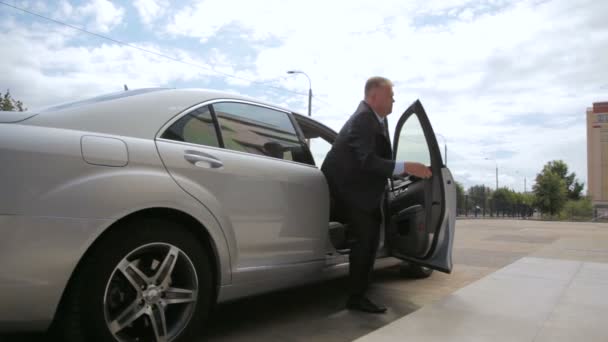 Homme en costume aide le directeur à sortir de voiture au bureau — Video