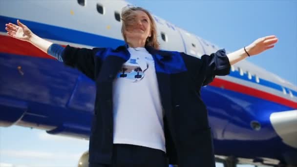 Chica feliz en uniforme de aeropuerto baila contra el avión — Vídeos de Stock