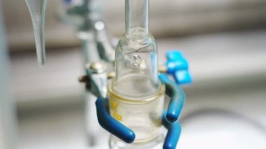 Closeup berrak sıvı aşağı laboratuvar cam ampul duvarı boyunca petrol tesisi modern kızgın yağ Distiller'da haşlanmış içine akar