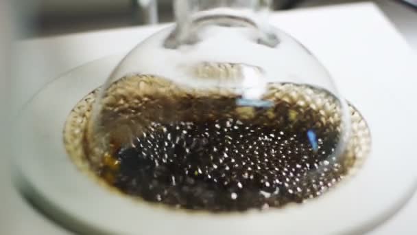 特写黑色液体升华与实验室工具和明确的石油流下降从玻璃站在桌子上 — 图库视频影像