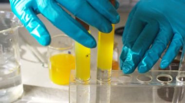 Portre asistanı plastik sarı siyah ve sıvı yağ laboratuvar tüplerde ı mahkemeye mavi eldiven eller