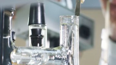 Closeup büyük uzun cam tüp modern bitki laboratuvar içine küçük dikdörtgen metal plakalar zincir koymak