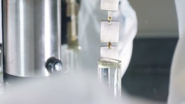 Ağır çekim portre adam asistan sıvı Ürün İnceleme işleminde aracıyla modern laboratuvar içine metal parçaları koyar