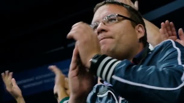 Zwolnionym tempie fan hokeja w okularach klaszcze w ręce na trybunach areny — Wideo stockowe