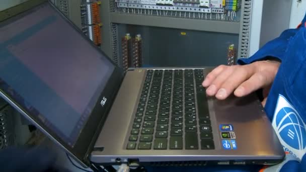 Trabalhador conecta notebook para controlar equipamentos elétricos no gabinete — Vídeo de Stock