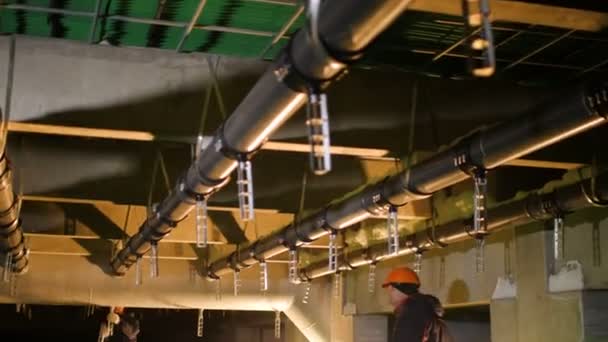 Werknemer verbindt metalen details aan pijpleiding in fabriek — Stockvideo