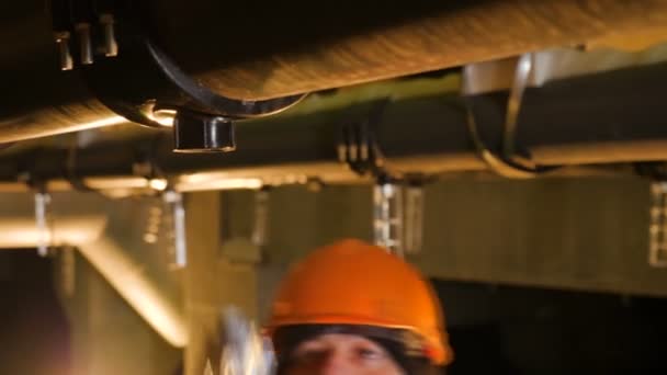 Lavoratore gira intorno parte sul tubo dell'impianto in officina — Video Stock