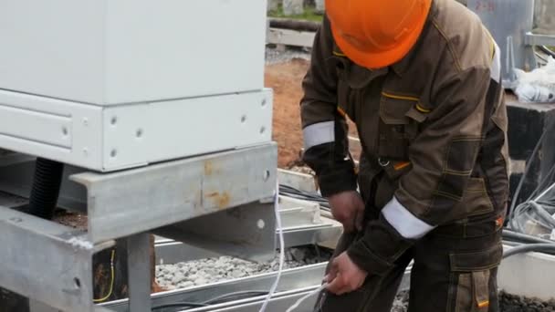 Dipendente in casco uniforme prepara il cavo per il montaggio tramite palo metallico — Video Stock