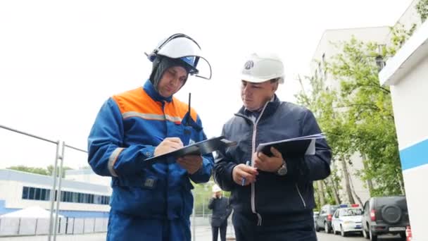 Ingenieure in Helmen prüfen Bericht über Werksgelände — Stockvideo
