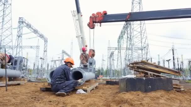 Zaměstnanci se připojí velké trubice na jeřábový hák na místě — Stock video