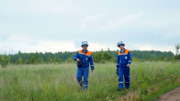 Сотрудники компании ходят по травяному полю по проселочной дороге — стоковое видео