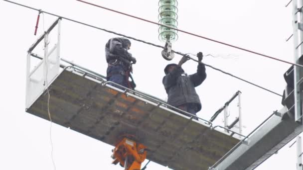 Los erectores montan alambres en la línea de transmisión aérea por la guirnalda de los aisladores — Vídeos de Stock