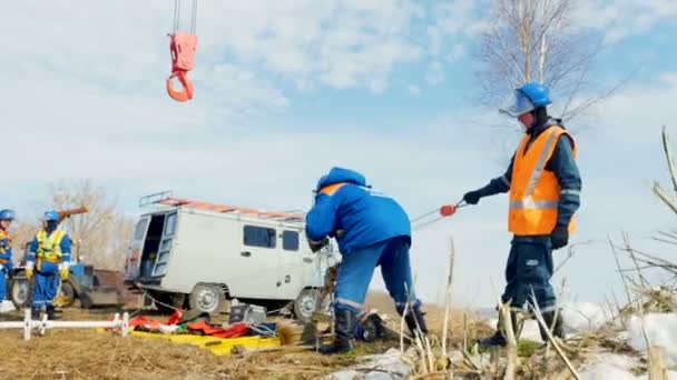 Empleados sostienen cuerdas de grúa cerca de furgoneta contra el cielo — Vídeos de Stock