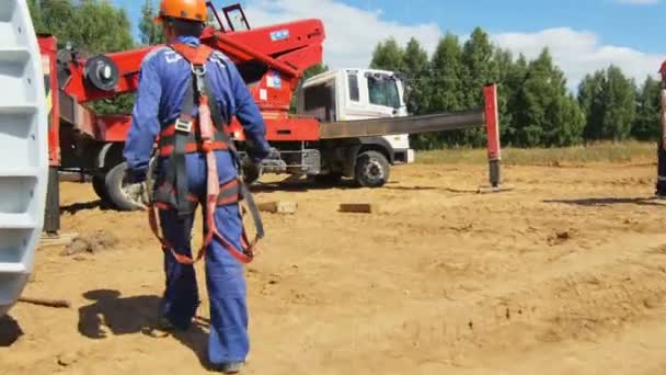 Arbetaren kommer och hamnar i lastbilen kran vagga — Stockvideo