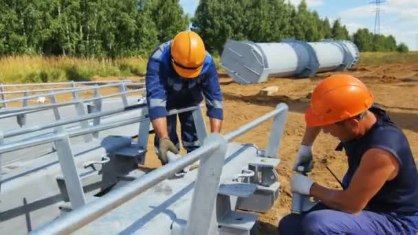 Os trabalhadores montam suportes elétricos no local de terra marrom — Vídeo de Stock