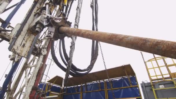 Los trabajadores controlan la elevación de tuberías por la máquina de perforación exploratoria de petróleo bajo nubes — Vídeo de stock