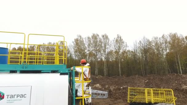 Employé en tenue monte échelle à réservoir avec des produits chimiques par des bouleaux — Video