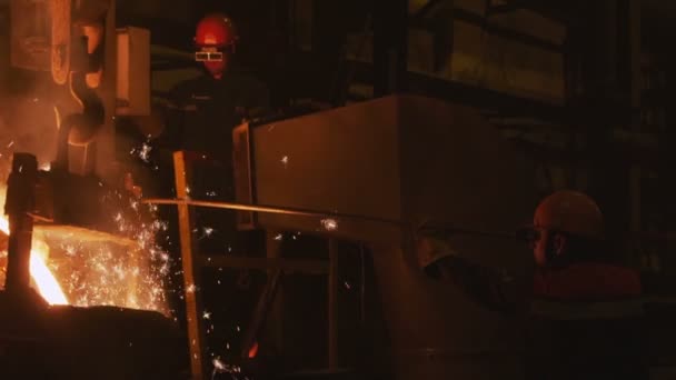 Gorący metal wlewa się do formy i pracownik w okularach w tle — Wideo stockowe