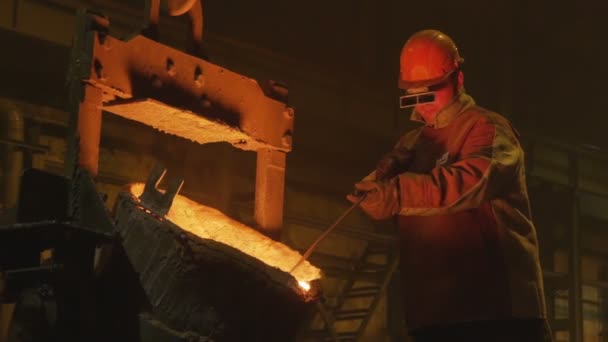 Worker turns bucket and metal pours against darkness — Stock Video