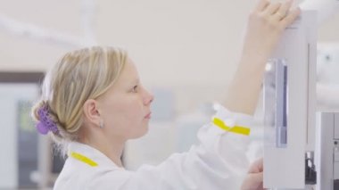 Kazan, Tataristan Rusya - 4 Nisan 2018: Portre sarışın kız asistan beyaz elbise içinde 4 Nisan kazan kimya fabrikasını Laboratuvarı modern ekipman üzerinde deneyler yapıyor