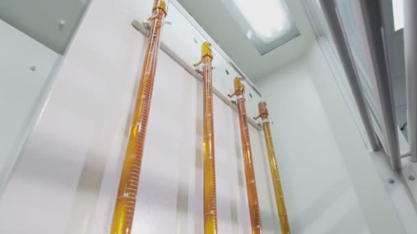 Lab assistant agitates liquid in chemical jar by dispenser for filling liquids — Stock Video