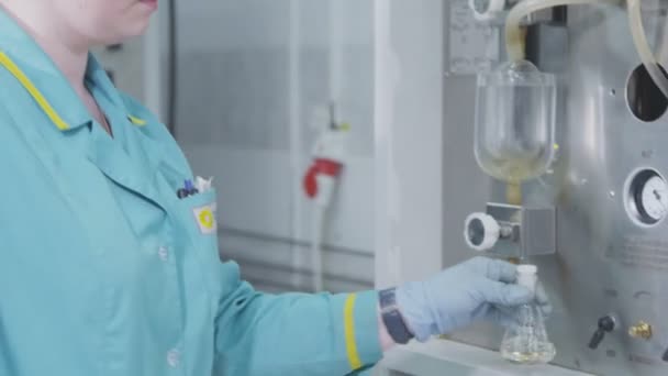 Closeup blonďatá dívka v azure roucho zkoumá kapalného vzorku v baňce v laboratoři — Stock video