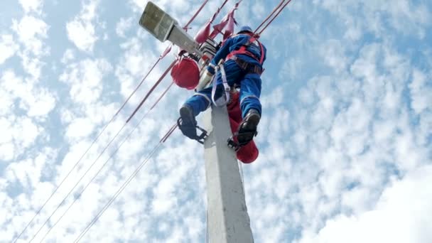 Працівник в наряд ногу праски з інструментом kit піднімається вгору пост проти мальовничих хмари — стокове відео