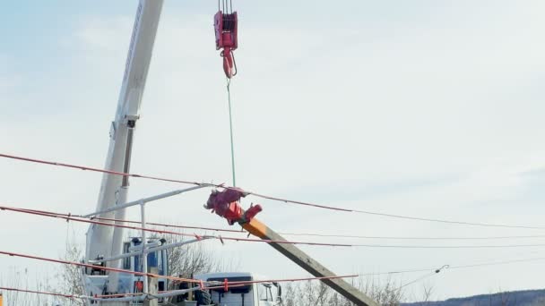 Electric pole lifted up with crane hook by village in winter — Stock Video