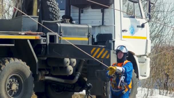 Електромонтажник тримає кабель поруч Лоррі серед сніг на землі — стокове відео