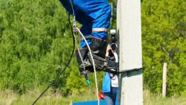 Competitor climbs up on electric pole to help mannequin — Stock Video