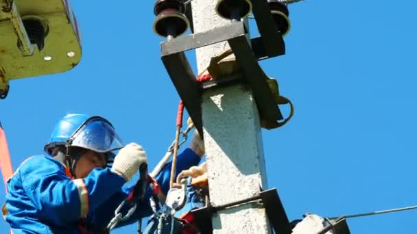 Werknemer installeert apparatuur op elektrische paal boven op wedstrijden — Stockvideo