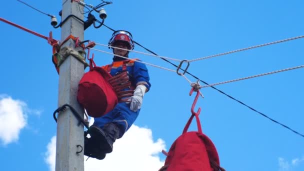 Electricista-instalador fijado en poste espera para el levantamiento especial de la bolsa de herramientas roja — Vídeos de Stock