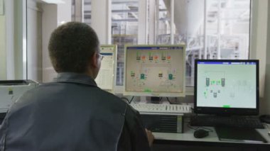 mühendis üretim Atölyesi karşı bilgisayar ekranları önünde oturur