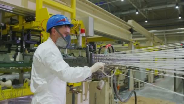 Arbeiter mit Atemschutzmaske läuft an beweglichen Fäden in Produktionshalle entlang — Stockvideo
