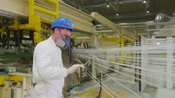 Arbeiter in Atemschutzmaske überprüft in moderner Werkstatt Zugkraft der Fäden — Stockvideo