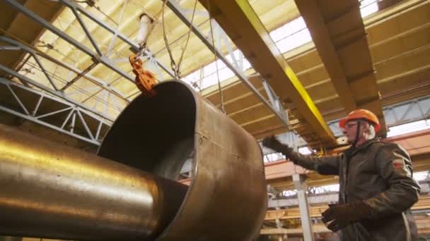 Trabajador controla gran parte del tubo puesto en tubo más delgado por la grúa — Vídeos de Stock