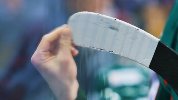 Хоккеист крупным планом чистит клюшки от частей ленты на арене — стоковое видео