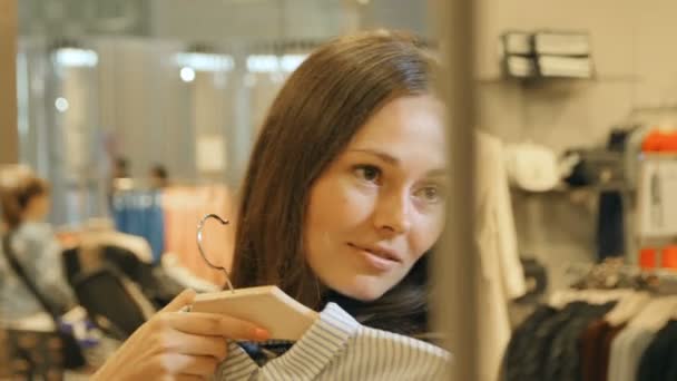 Lächelndes Mädchen probiert Kleider im Spiegel mit Freund an — Stockvideo