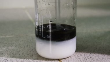 closeup laboratuvar çalışan beyaz madde ve ham petrol cam karıştırmak çalışır