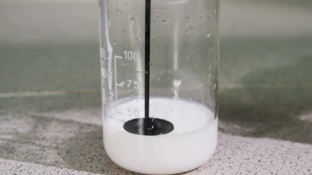 Сырая нефть крупным планом вливается в стакан с белой плотной жидкостью — стоковое видео