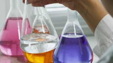 closeup laboratuar işçisi doldurur ve test edilmiş sıvı ile cam sallar