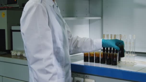 Mouvement passé assistant de laboratoire remplissage de tubes avec de l'huile sur le lieu de travail — Video