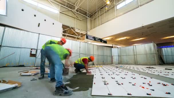 Zkušení tvůrci dát keramické dlaždice na vlhké betonové podlaze timelapse — Stock video