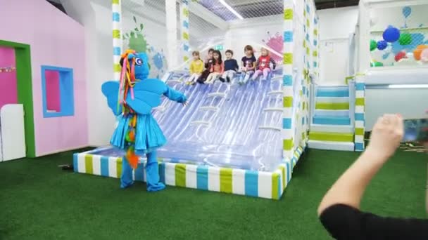 Animator in blauwe pony pak speelt met de kinderen op de eerste dia — Stockvideo