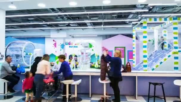 Родители помогают детям раздеться в яркой цветной игровой комнате — стоковое видео