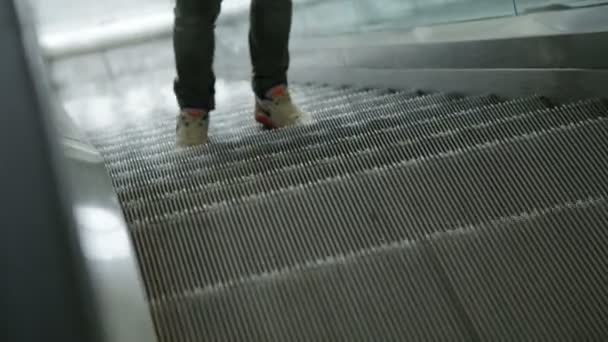 Closeup jongeman voeten in witte snickers op roltrap — Stockvideo