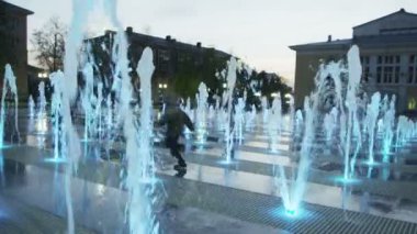 Çocuklar çeşmeler ile mavi ışık ve müzik atlama üzerinden çalıştırmak