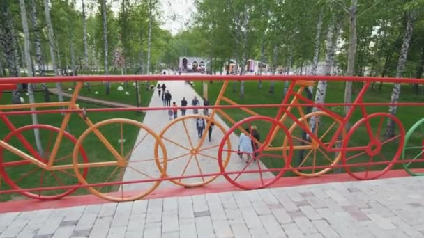 Vista da ponte com corrimãos de bicicleta em pessoas no parque — Vídeo de Stock