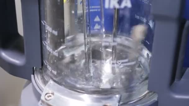 Cerrar vista líquido transparente mezclado en vaso de precipitados de vidrio alto — Vídeo de stock