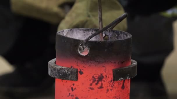 Close view container with molten silver metal held by clamp — Stock Video